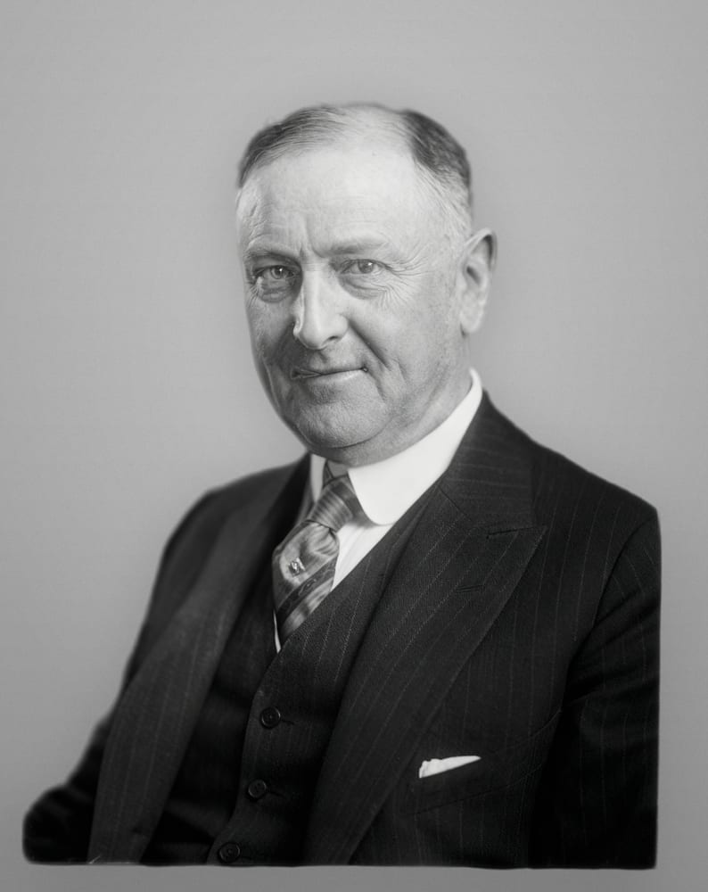 The same portrait restored, with the flaking and streak cleaned and a plain studio background. The face is unchanged.
